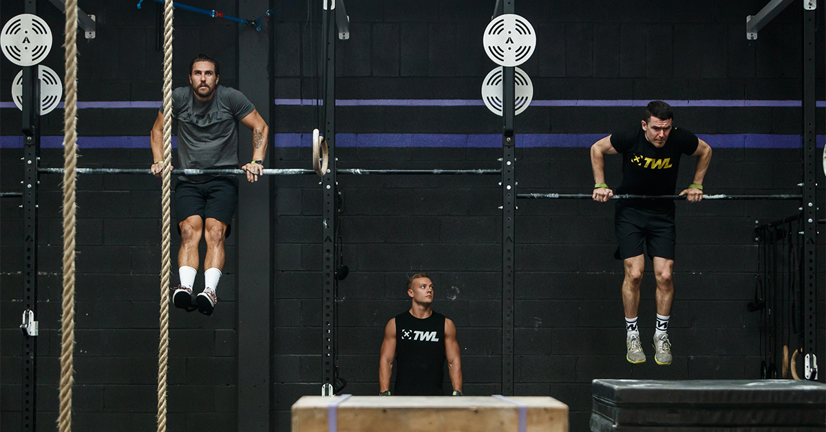 two male athletes doing pull-ups